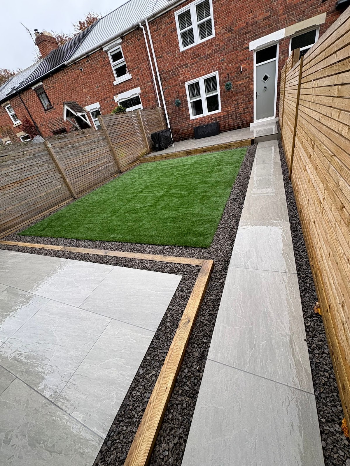 Porcelain paving, artificial lawn and slate borders in a garden built by Elite Landscaping NE in Durham