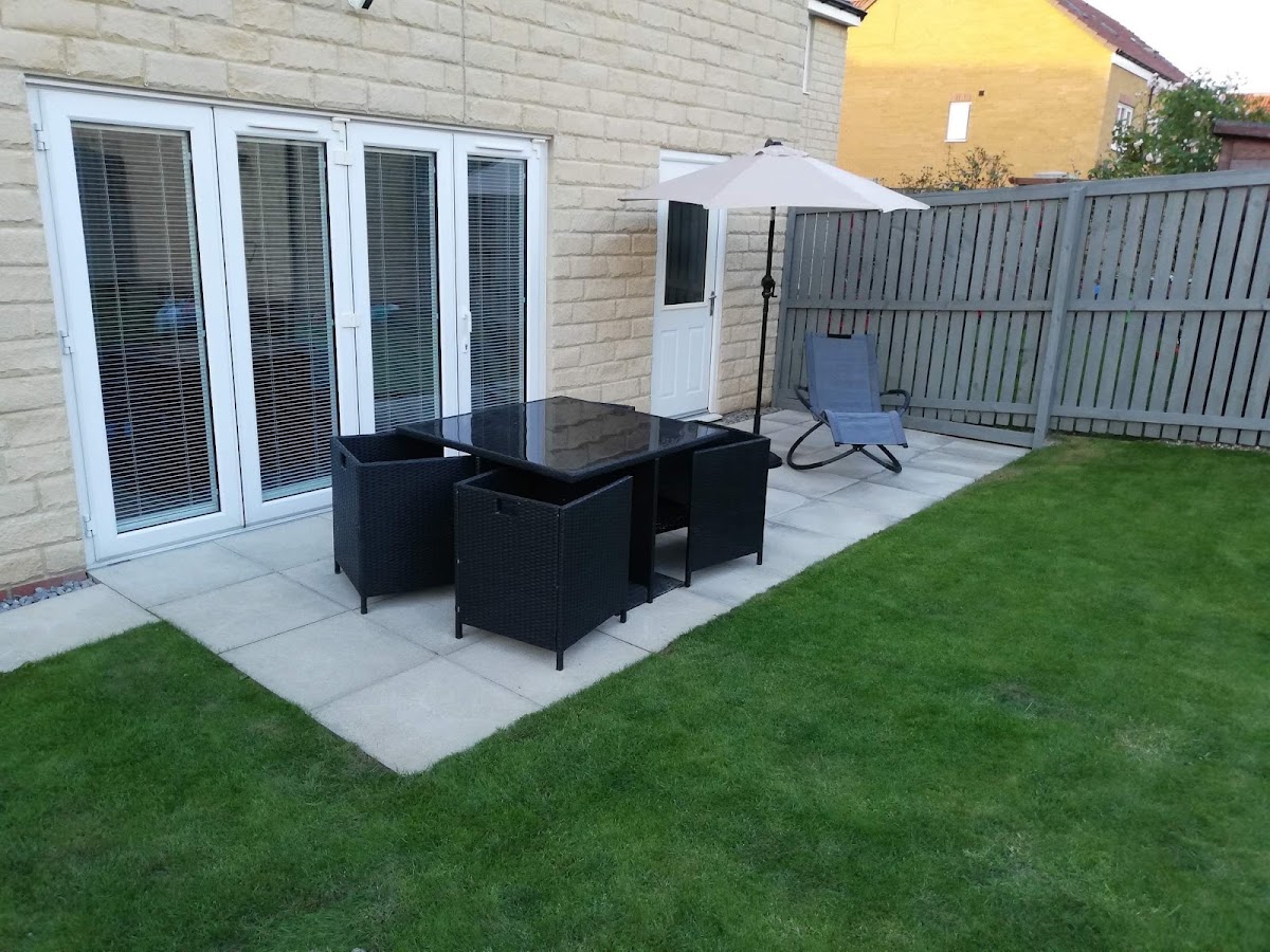 Paved patio and fresh turf with garden furniture set out