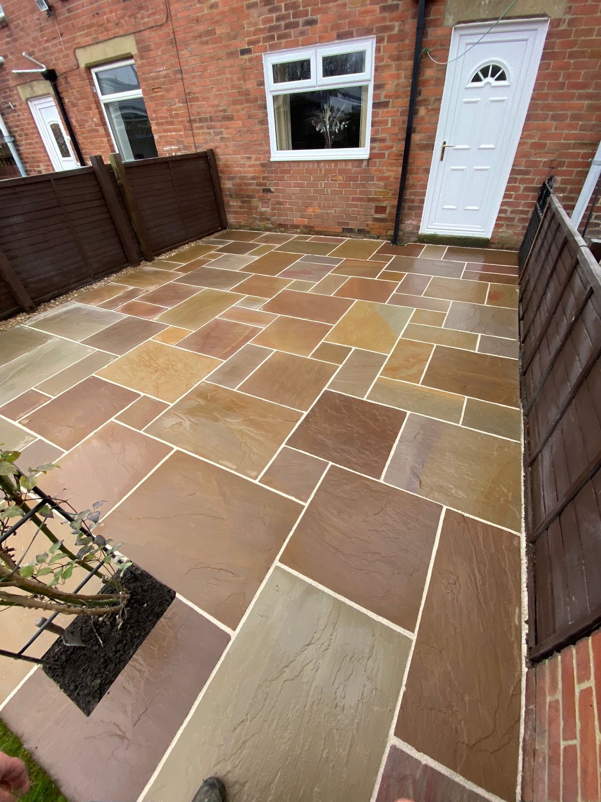 Multi tone Indian sandstone patio laid to the rear of a terraced house
