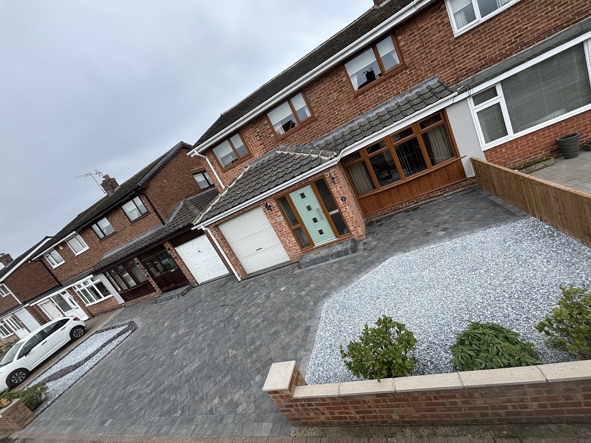 Block paved driveway with a silver grey gravel bed and brick retaining wall